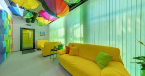 a living room with a yellow couch and colorful umbrellas at Green Cube Capsule Hostel in Sofia