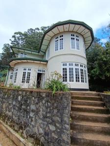 a large white house with a stone wall at Magnolia Hideout in Nuwara Eliya