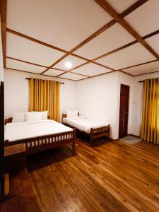two beds in a large room with wooden floors at Magnolia Hideout in Nuwara Eliya