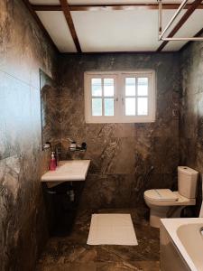 a bathroom with a toilet and a sink and a window at Magnolia Hideout in Nuwara Eliya