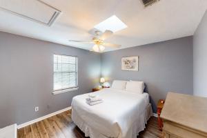 a bedroom with a white bed and a ceiling fan at Island Retreat in St. George Island