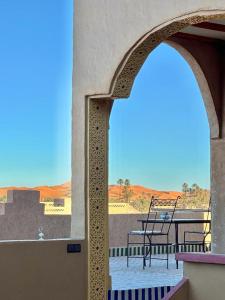 an archway with a table and chairs on a balcony at Camels House in Merzouga