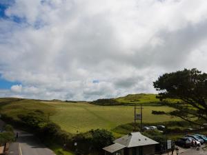 a view of a green hill with cars parked on a street at The Smugglers Rest in Woolacombe