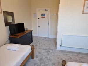 1 dormitorio con cama y vestidor con TV en The Menai Hotel and Bar, en Bangor