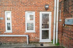a brick wall with a door and three windows at Large studio 2min to hendon Central Station in The Hyde