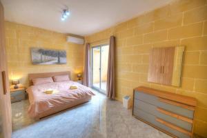 um quarto com uma cama e uma parede amarela em 36, Serina Court - Marsalforn, Gozo - Malta em Marsalforn