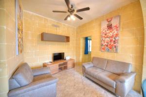 uma sala de estar com 2 sofás e uma televisão de ecrã plano em 36, Serina Court - Marsalforn, Gozo - Malta em Marsalforn