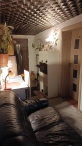 uma sala de estar com um sofá de couro e um frigorífico em хостел em Poznań
