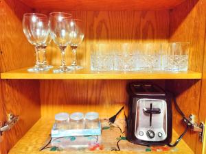 una estantería con copas, tostadora y copas de vino en Lovely suite, en Surrey