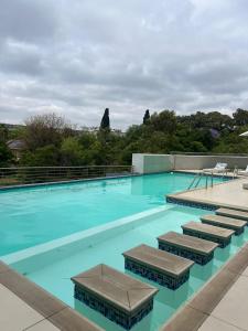 una gran piscina con agua azul y sillas en REGENCY APARTMENT HOTEL-ST@Y en Pretoria