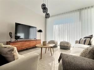 un salon avec une télévision, un canapé et une table dans l'établissement San Roque Golf Club, Step into elegance with this 3-bedroom luxury modern townhouse close to Sotogrande, à San Roque