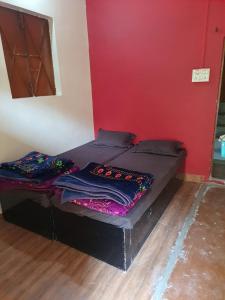 a small bed in a room with a red wall at Mahakaal HomeStay in Ujjain