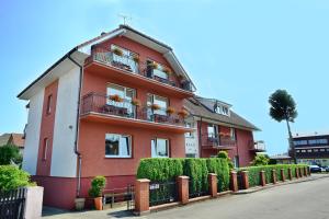 un edificio rosso con balconi e piante sopra di Dom Gościnny Relax a Rewal