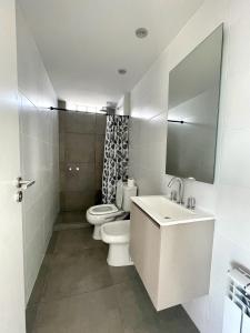 een badkamer met een toilet, een wastafel en een spiegel bij Hermoso departamento a estrenar in Mar del Plata