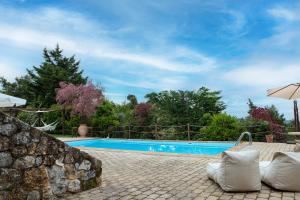 a pool with chairs and an umbrella next to a stone wall at Maison Christine Villa in Varnávas
