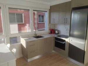 Una cocina con gabinetes blancos y un refrigerador negro. en Apartamento Bulevar Cangas, en Cangas de Morrazo 4 fotos más