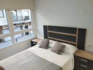 Un dormitorio con una cama con dos almohadas y una ventana. en Apartamento Bulevar Cangas, en Cangas de Morrazo