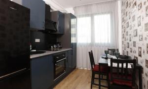 uma cozinha com uma mesa e um frigorífico preto em Apartament Modern Ivory Pipera em Voluntari