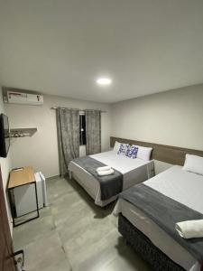 Habitación de hotel con 2 camas y TV en Brisa dos Anjos Suítes en Arraial do Cabo
