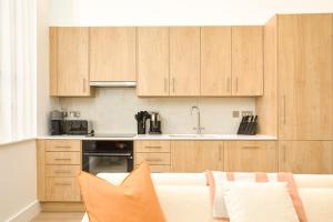 a kitchen with wooden cabinets and a couch at Be London - Marylebone Apartments in London