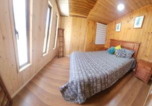 um quarto com uma cama num chalé de madeira em Cabaña Familiar 3 dormitorios 1 baño gran espacio para compartir em El Quisco