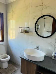 a bathroom with a sink and a toilet and a mirror at Pine View Guesthouse Graskop in Graskop