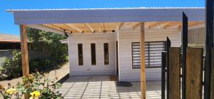 um pequeno barracão branco com um telhado de madeira em Cabaña Familiar 3 dormitorios 1 baño gran espacio para compartir em El Quisco