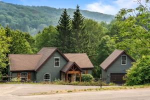 a house in the woods with mountains in the background at Gorgeous 5 Bdr with Hot Tub - Walk to Holi-Mont! in Ellicottville