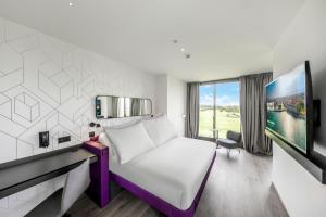 a hotel room with a bed and a tv at YOTEL Geneva Lake in Founex