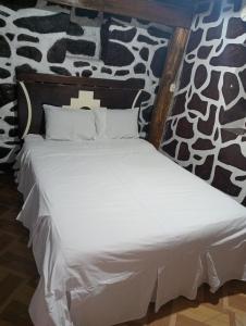 a bed with white sheets and pillows in a room at Sacred Point in Ollantaytambo