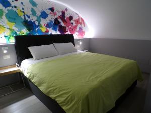 ein Schlafzimmer mit einem grünen Bett und einer farbenfrohen Wand in der Unterkunft GRAZIA’S HOUSE in Mistretta