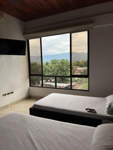 um quarto com 2 camas e uma grande janela em Casa Raices em La Dorada