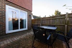 a patio with a table and chairs next to a fence at One Bridge End in Pevensey