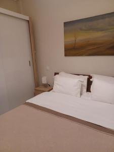 een slaapkamer met een wit bed en een schilderij aan de muur bij Irida Equanimity and Cozy Apartment in Thessaloniki