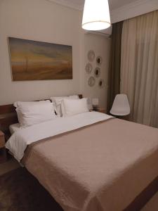 een slaapkamer met een groot wit bed en een lamp bij Irida Equanimity and Cozy Apartment in Thessaloniki