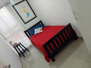 a bedroom with a bed with a red blanket and a window at A minutos del centro Con cochera in Trujillo
