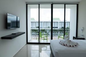 1 dormitorio con 1 cama y balcón con TV en Hotel & Suites Yuca Ville Siglo XXI, en Mérida