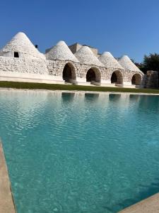 una fila de edificios abovedados con agua en el primer plano en Masseria Castelluzzo, en Ceglie Messapica