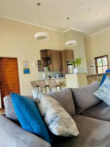 a living room with a gray couch with blue pillows at Pine View Guesthouse Graskop in Graskop