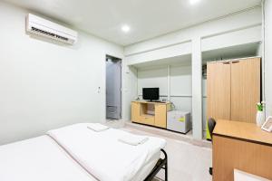 um quarto com uma cama, uma secretária e uma televisão em Freesia Saladaeng Silom Apartments em Bangkok