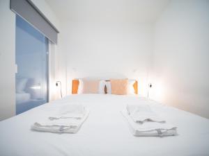 a bedroom with a white bed with two towels on it at Oporto City View- Trindade luxury in Porto