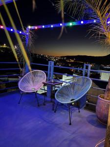 3 Stühle und ein Tisch auf dem Balkon in der Nacht in der Unterkunft USHA Guest House in Chefchaouen