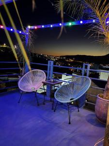 three chairs and a table on a balcony at night at USHA Guest House in Chefchaouene