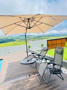 una mesa y dos sillas y una sombrilla en una terraza en Pine View Guesthouse Graskop, en Graskop