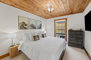een slaapkamer met een wit bed en een houten plafond bij New & Stunning Chalet! Reno'd, Hot-Tub, Barrel Sauna, Slope Views, Fire Pit in Ellicottville