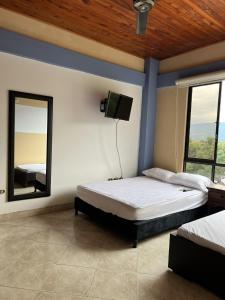 a bedroom with two beds and two windows at Casa Raices in La Dorada