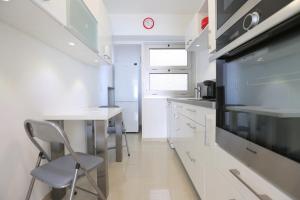 a kitchen with white cabinets and a table and a tv at BRIDGESTREET MONACO - cap d ail - roquebrune in Saint-Antoine