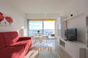 a living room with a red couch and a table at BRIDGESTREET MONACO - cap d ail - roquebrune in Saint-Antoine