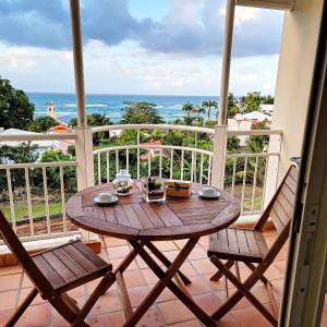 a table on a balcony with a view of the ocean at Studio climatisé dans Résidence avec piscine, à proximité de la mer in La Trinité