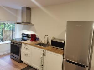 uma cozinha com um frigorífico de aço inoxidável e um lavatório em Garden Home em Surrey